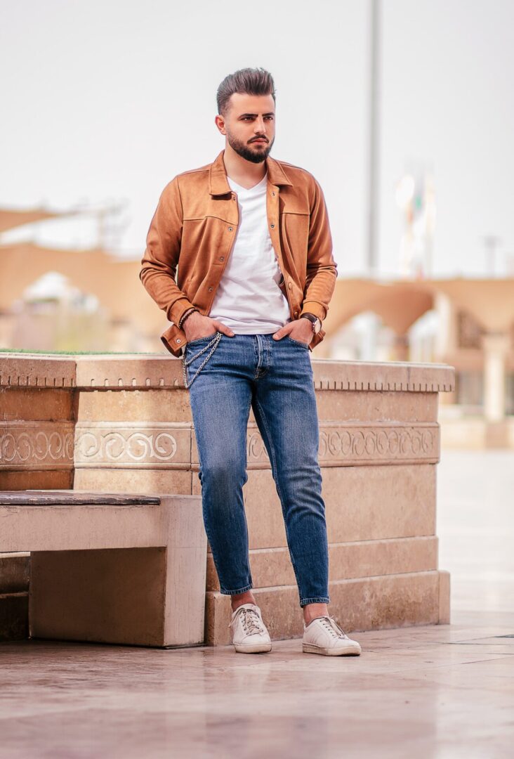 Man in a tan jacket and Pants standing confidently on a city street.